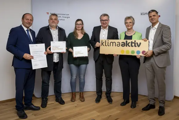 mehrere Personen mit Urkunde in der Hand schauen in die Kamera
