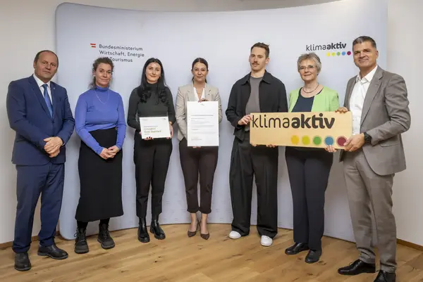 mehrere Personen mit Urkunde in der Hand schauen in die Kamera