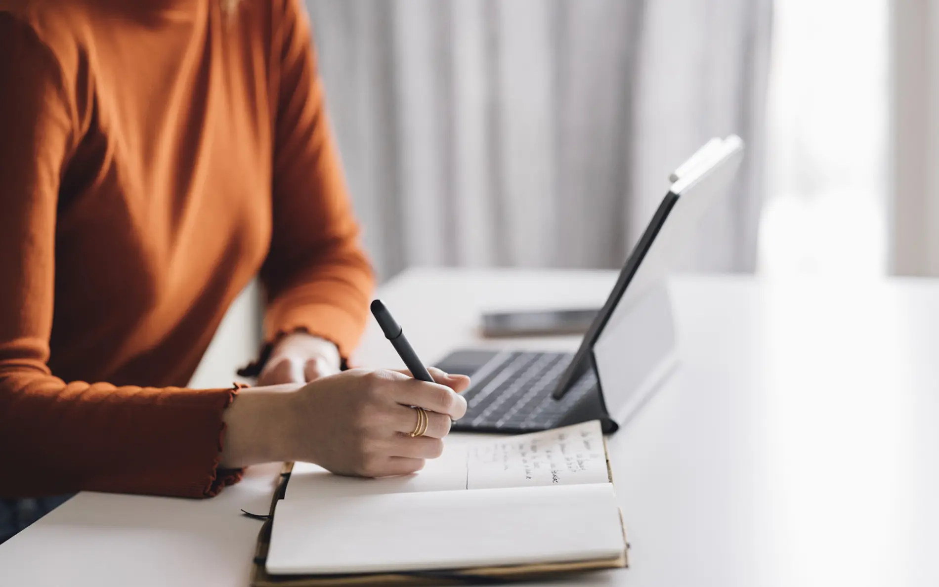 Eine Frau sitzt beim Schreibtisch und liest auf ihrem Laptop