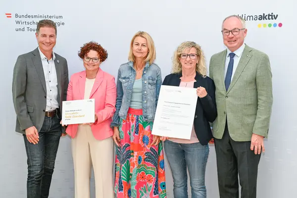 Personen mit Urkunde schauen in die Kamera