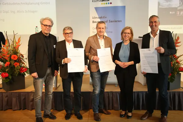 Ministerin Leonore Gewessler überreicht Urkunden an Bauherr, Techniker und Architekt