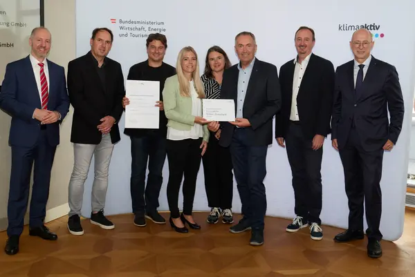 8 Personen mit Urkunde schauen in die Kamera