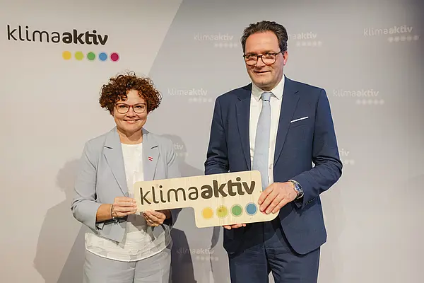 Menschen mit Urkunde und klimaaktiv Schild lächeln in die Kamera