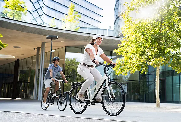 Zwei Menschen auf dem Fahrrad in einer städtischen Umgebung