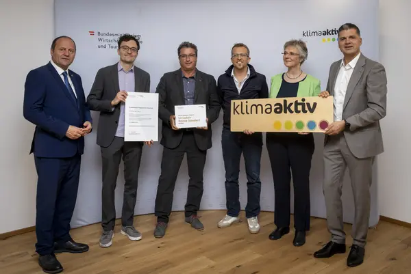 mehrere Personen mit Urkunde in der Hand schauen in die Kamera