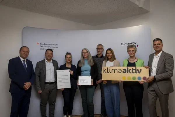 Menschen mit Urkunde schauen in eine Kamera