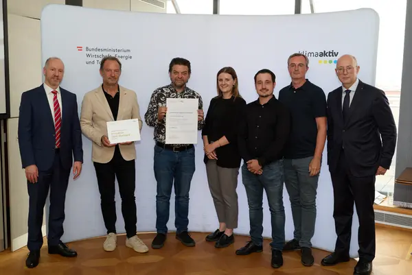 7 Personen mit Urkunde schauen in die Kamera