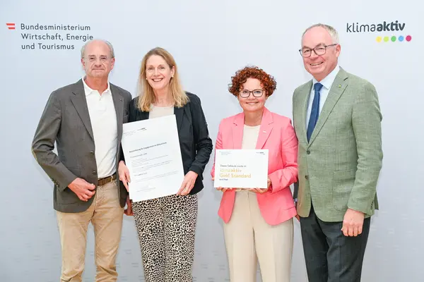 Personen mit Urkunde schauen in die Kamera