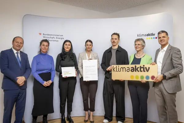 mehrere Personen mit Urkunde in der Hand schauen in die Kamera