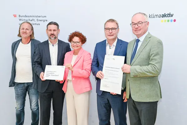 Personen mit Urkunde schauen in die Kamera