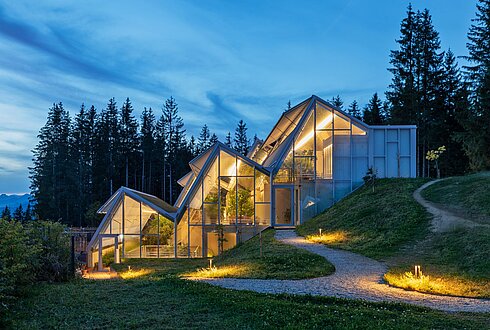 Das Glashaus des Restaurants von außen bei Nacht.