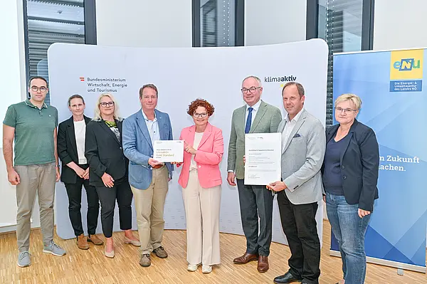 Personen mit Urkunde schauen in die Kamera