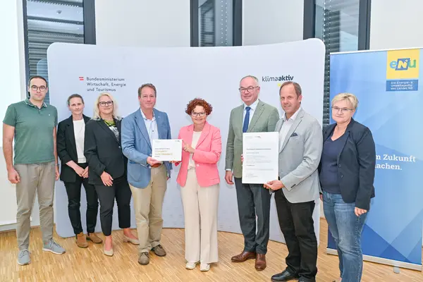 Personen mit Urkunde schauen in die Kamera