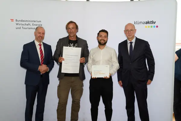 4 Personen mit Urkunde schauen in die Kamera