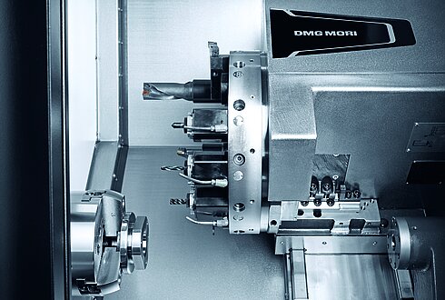 Detailansicht einer CNC-Drehmaschine mit Werkzeughalter und Spannfutter, glänzende Metalloberflächen.