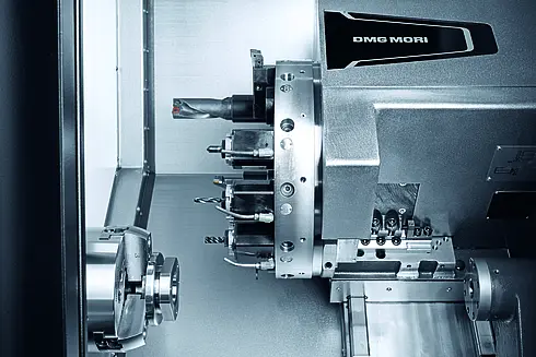 Detailansicht einer CNC-Drehmaschine mit Werkzeughalter und Spannfutter, glänzende Metalloberflächen.