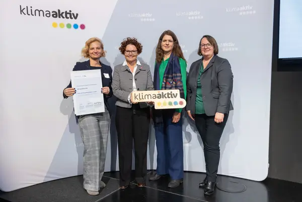 4 Personen mit Urkunde und klimaaktiv Schild schauen in die Kamera