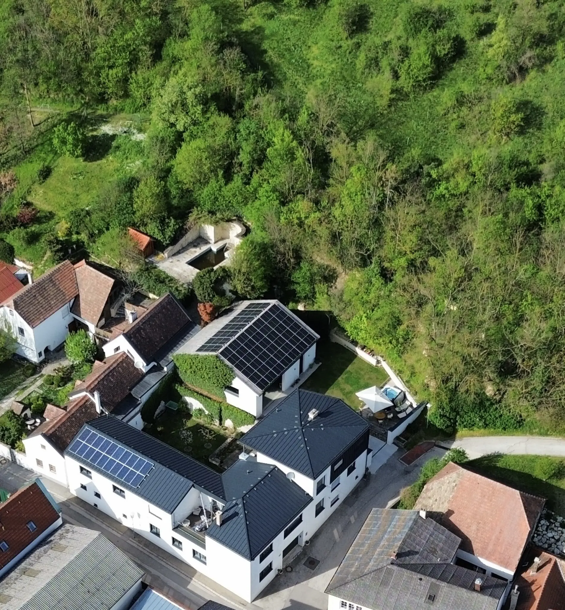 Die Vogelperspektive eines Vier-Kant-Hofes. Auf den Dächern sind mehrere PV-Paneele zu sehen