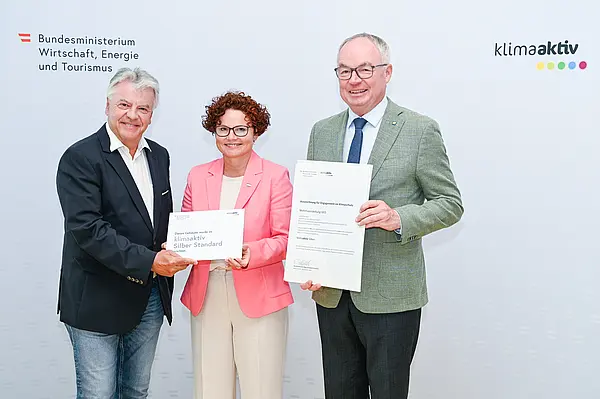 Personen mit Urkunde schauen in die Kamera