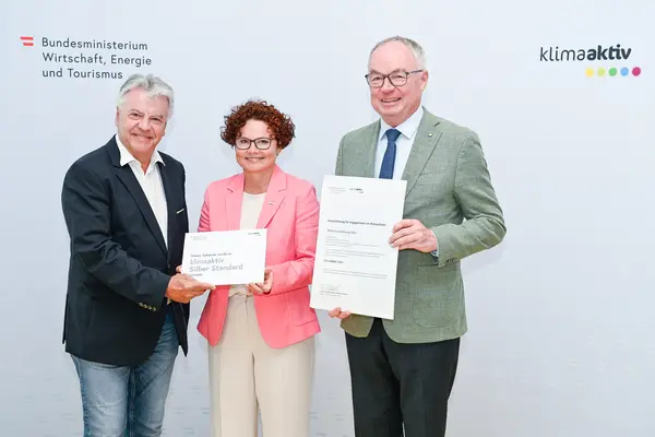 Personen mit Urkunde schauen in die Kamera