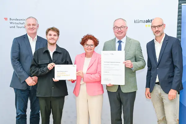 Personen mit Urkunde schauen in die Kamera