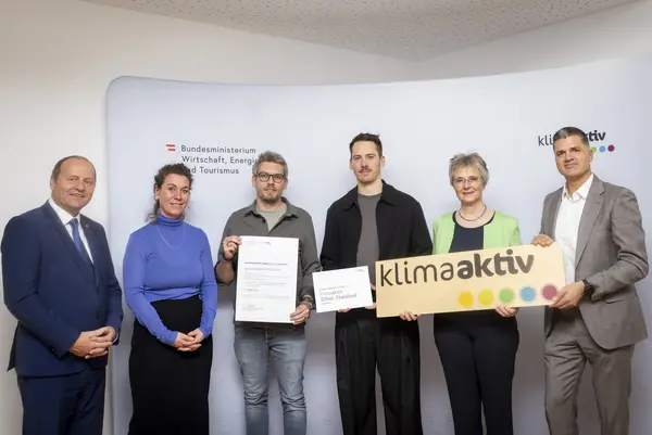 mehrere Personen mit Urkunde in der Hand schauen in die Kamera