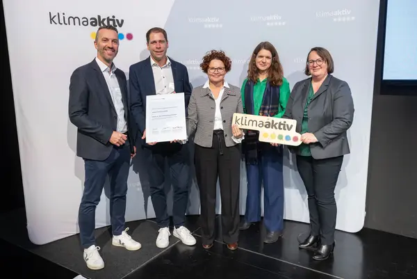 5 Personen mit Urkunde und klimaaktiv Schild schauen in die Kamera