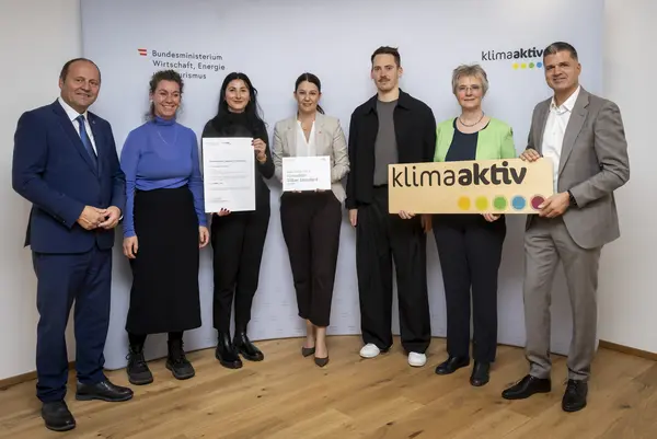 mehrere Personen mit Urkunde in der Hand schauen in die Kamera