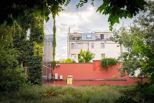 Ein Haus mit einer PV-Anlage an der Fassade und im Hintergrund ein mehrgeschossiges Haus.