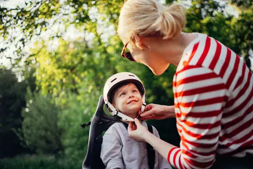 Eine Mutter macht ihrem Kind den Helm zu am Fahrradsitz