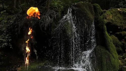 Feuer im Wald vor einem Wasserfall