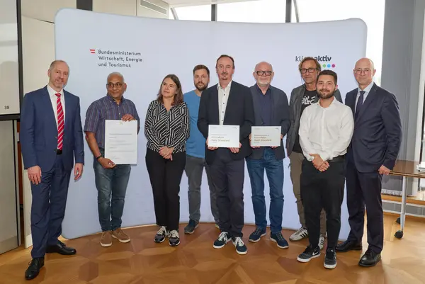 9 Personen mit Urkunde schauen in die Kamera