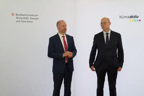 2 Männer in Anzug stehen vor einer Logowand klimaaktiv