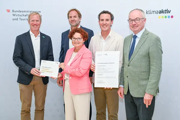 Personen mit Urkunde schauen in die Kamera