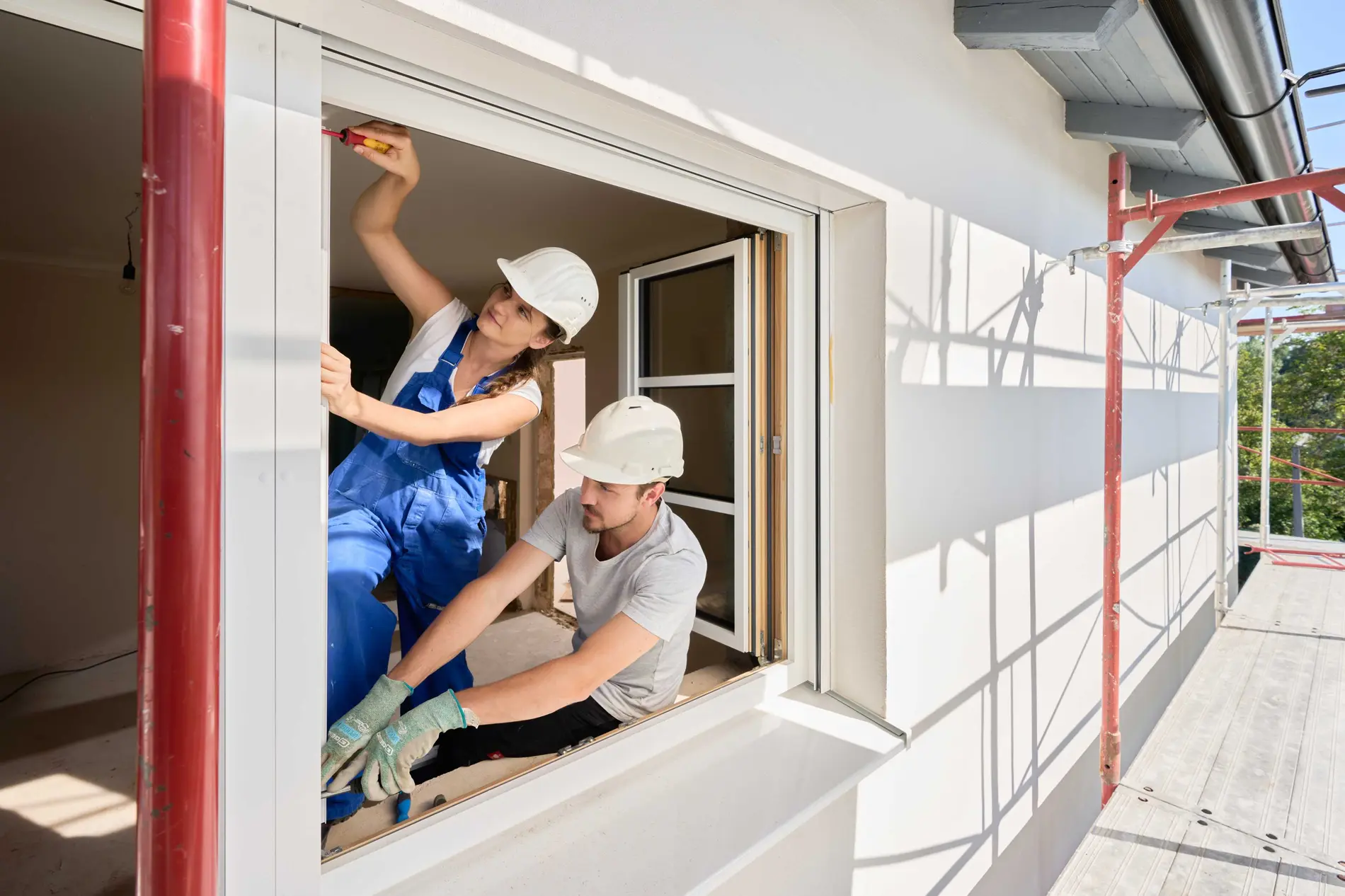 Eine Frau und ein Mann installieren gerade ein Fenster bei einem Haus