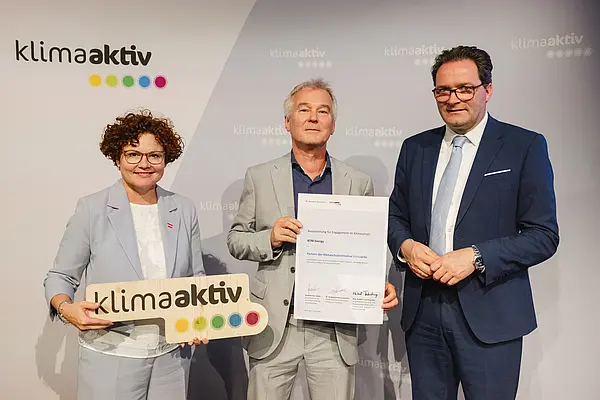 Menschen mit Urkunde und klimaaktiv Schild lächeln in die Kamera
