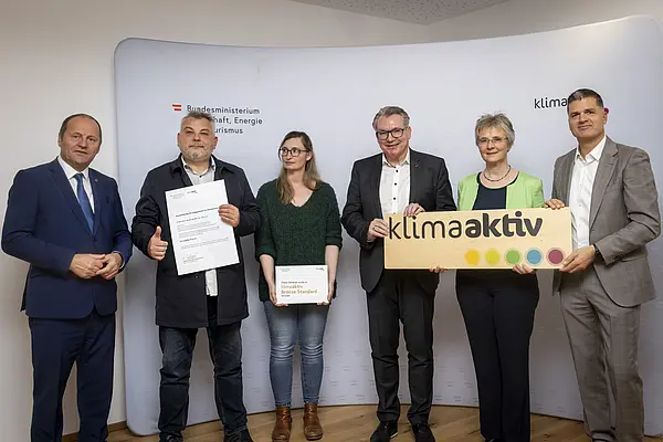 Menschen mit Urkunde schauen in eine Kamera