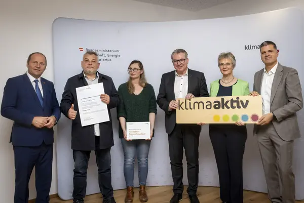 Menschen mit Urkunde schauen in eine Kamera