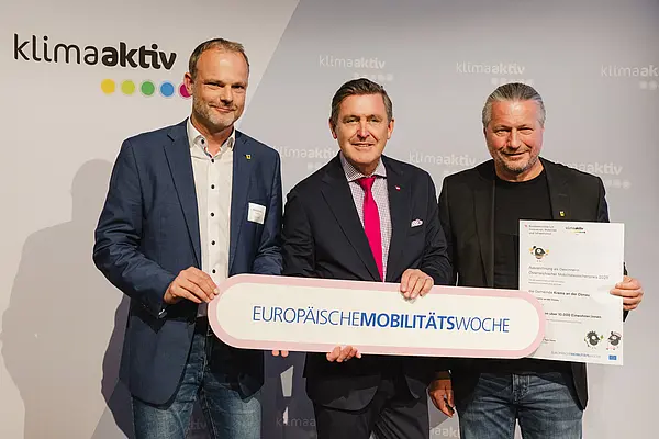 Menschen mit Urkunde und klimaaktiv Schild lächeln in die Kamera