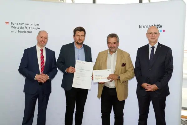 4 Personen mit Urkunde schauen in die Kamera