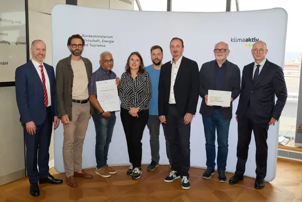 8 Personen mit Urkunde schauen in die Kamera