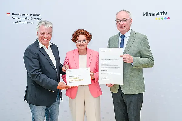 Personen mit Urkunde schauen in die Kamera