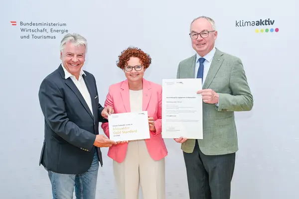 Personen mit Urkunde schauen in die Kamera