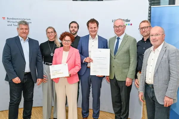 Personen mit Urkunde schauen in die Kamera