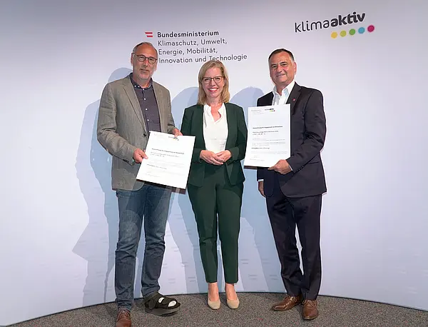 Im Bild: Klimaschutzministerin Leonore Gewessler, Vorstand Helmut Kusternik (meine heimat Gemeinnützige Bau-, Wohn- und Siedlungsgenossenschaft mbH), Roland Omann (Architekten Falle & Omann)