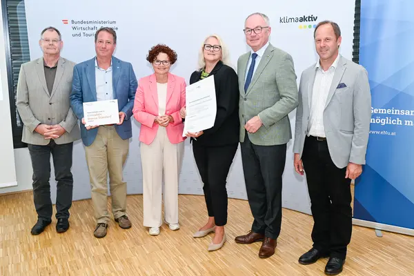 Personen mit Urkunde schauen in die Kamera