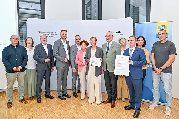 Personen mit Urkunde schauen in die Kamera