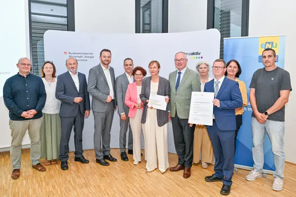 Personen mit Urkunde schauen in die Kamera