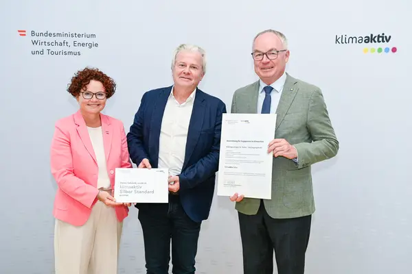 Personen mit Urkunde schauen in die Kamera