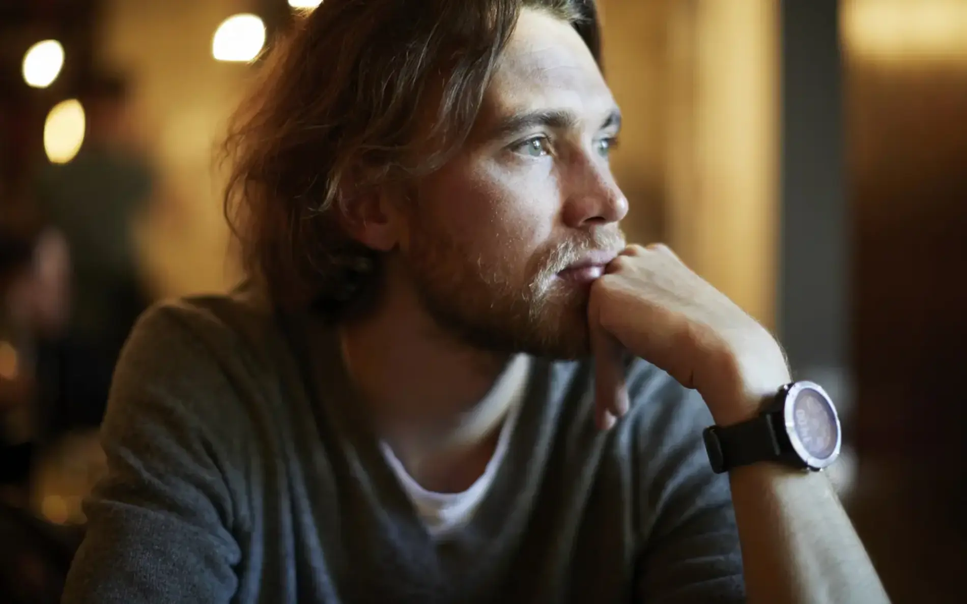 Ein Mann stützt mit seiner Hand sein Kinn und schaut in die Ferne